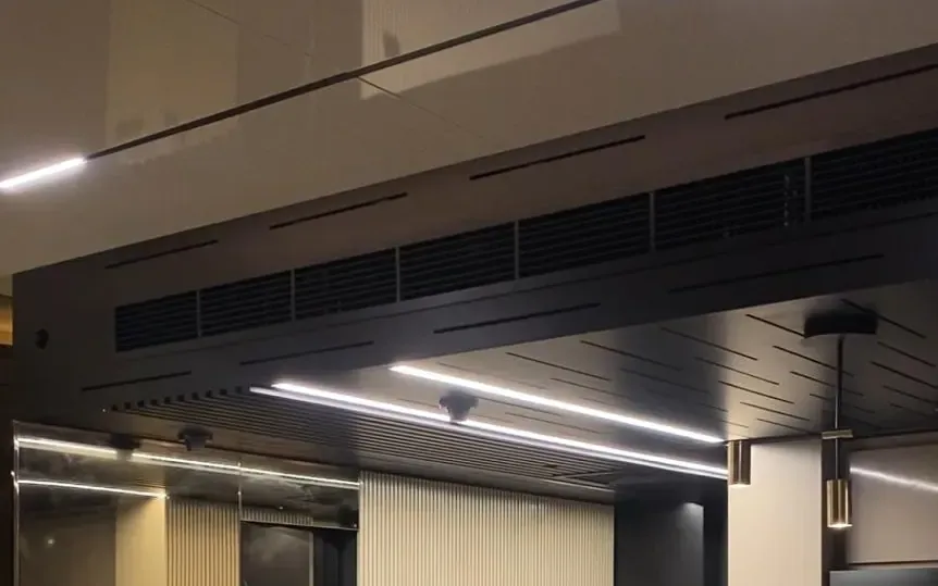 Suspended slat baffle ceiling with recessed linear lighting in a Dubai kitchen